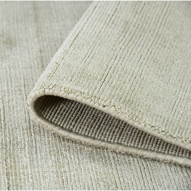 Rectangle area rug showing folded edge and dense striped weave in light sand tones.