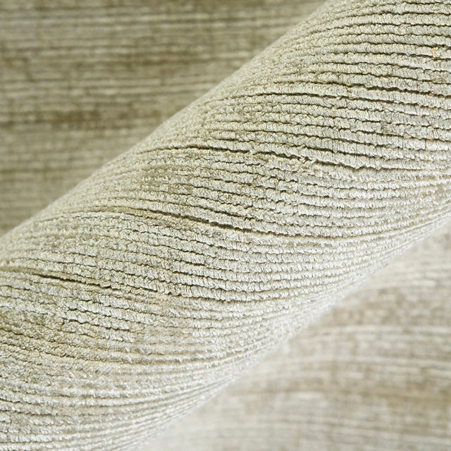 Striped hand-woven area rug corner with close-up texture and light sand color.