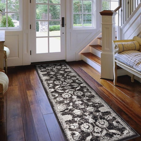Long rectangular black and ivory area rug with distressed floral geometric pattern