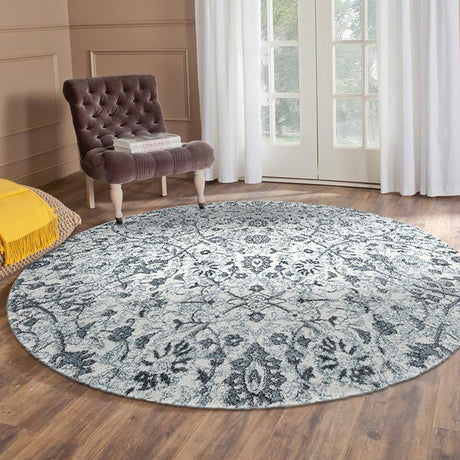 Light blue round floral area rug with ornate damask pattern in front of armchair
