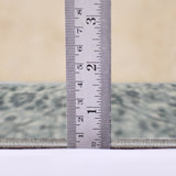 Light blue area rug edge with tape measure showing low pile height