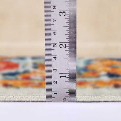 Ivory area rug edge with multicolor border; measuring tape shows low-pile thickness.