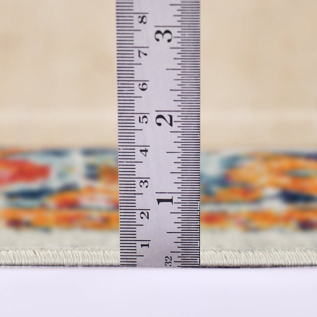 Ivory area rug edge with multicolor border; measuring tape shows low-pile thickness.