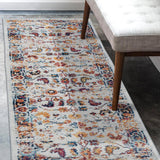 Narrow rectangular ivory area rug with multicolor medallion and bordered design.