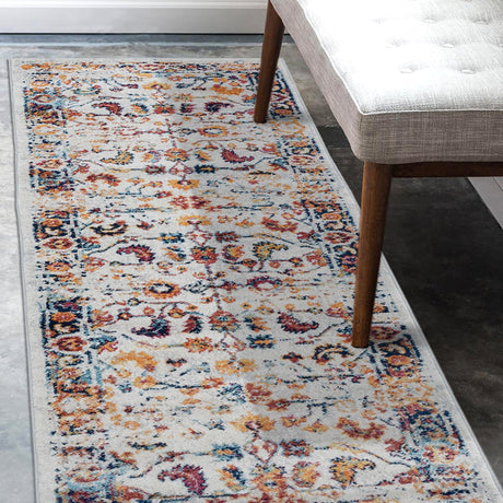 Narrow rectangular ivory area rug with multicolor medallion and bordered design.