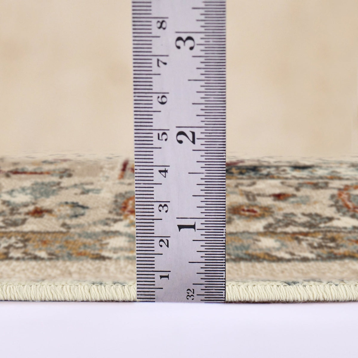 Ivory multi-color area rug shown with measurement tape across the border edge