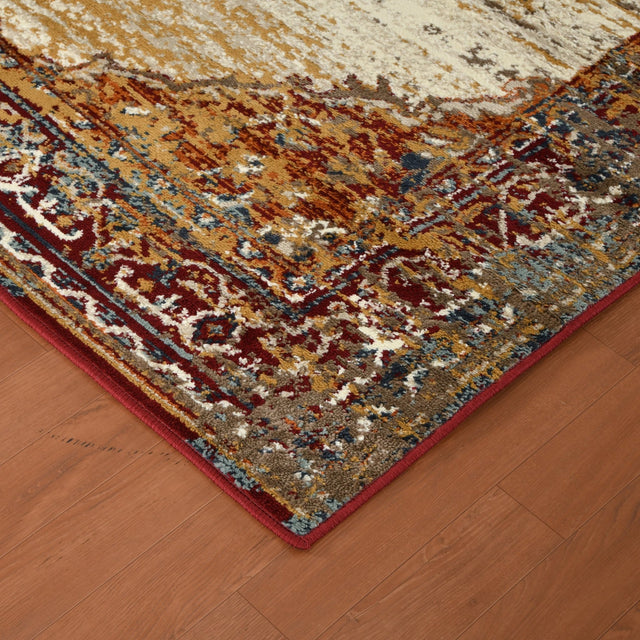 Corner of beige and multicolor distressed area rug with red bound edge on wood floor.