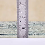 Ivory and blue area rug with stitched border, shown beside measuring ruler