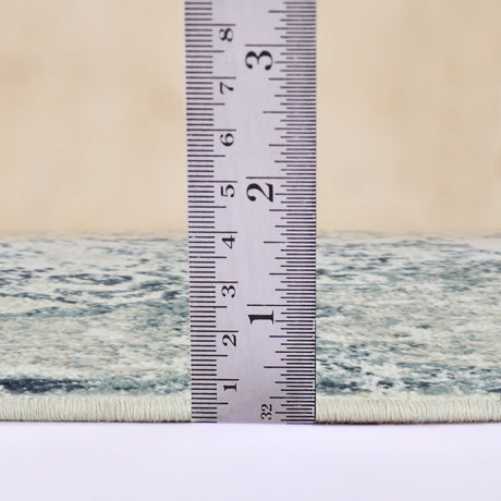 Ivory and blue area rug with stitched border, shown beside measuring ruler
