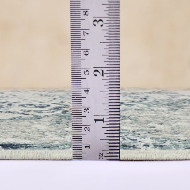 Ivory and blue area rug with stitched border, shown beside measuring ruler
