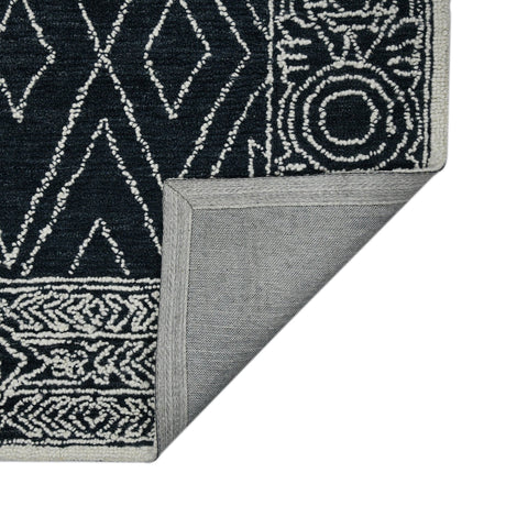 Rectangular area rug corner with charcoal-and-white geometric pattern and flat woven edge