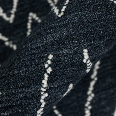 Rectangular area rug close-up showing dense looped pile and crisp white geometric accents