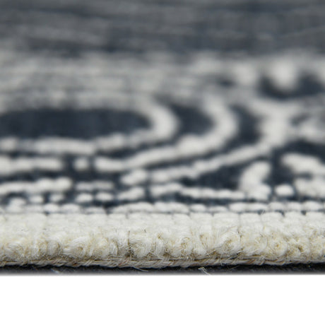 Rectangular area rug border close-up with charcoal/white geometric pattern and looped texture