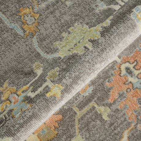 Close-up of taupe rug pattern with ornate geometric shapes in orange, blue, and yellow.