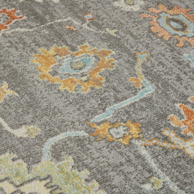 Taupe area rug with geometric medallion motifs in orange, blue, and yellow.