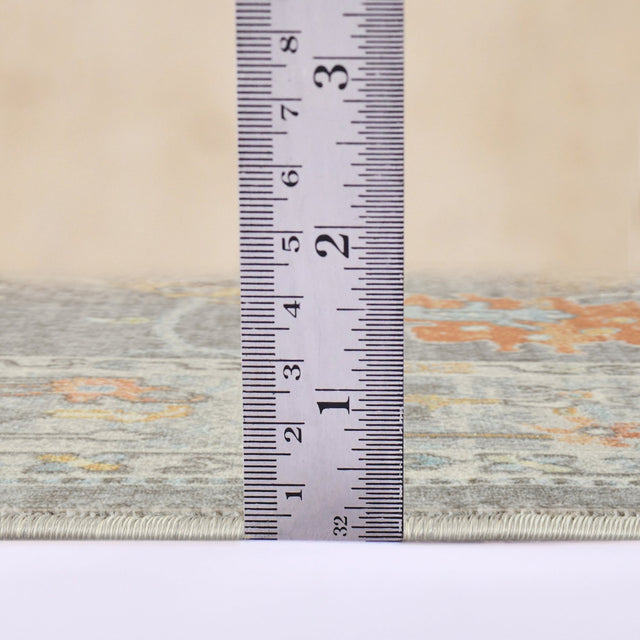 Taupe rug edge with visible binding; tape measure shows rug thickness/height.