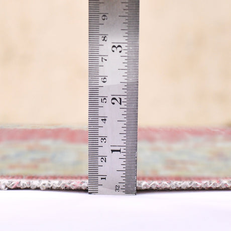 Rug with multicolor woven border edge, shown with a ruler beside the trim