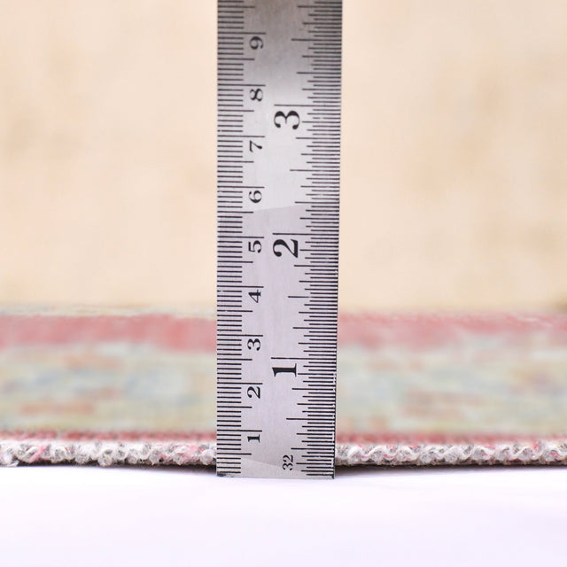 Rug with multicolor woven border edge, shown with a ruler beside the trim