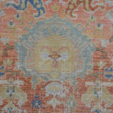 Close-up medallion pattern area rug in blue, coral, and ivory