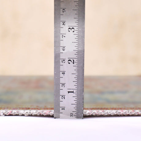Area rug edge with fringe, shown with measuring ruler for pile thickness