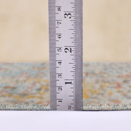 Teal area rug edge shown with measuring ruler for pile height