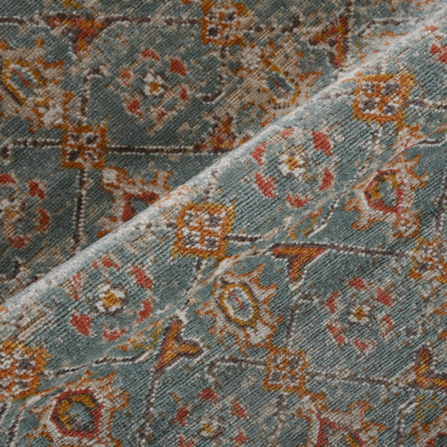Teal area rug close-up of distressed floral and geometric motifs in orange and gold