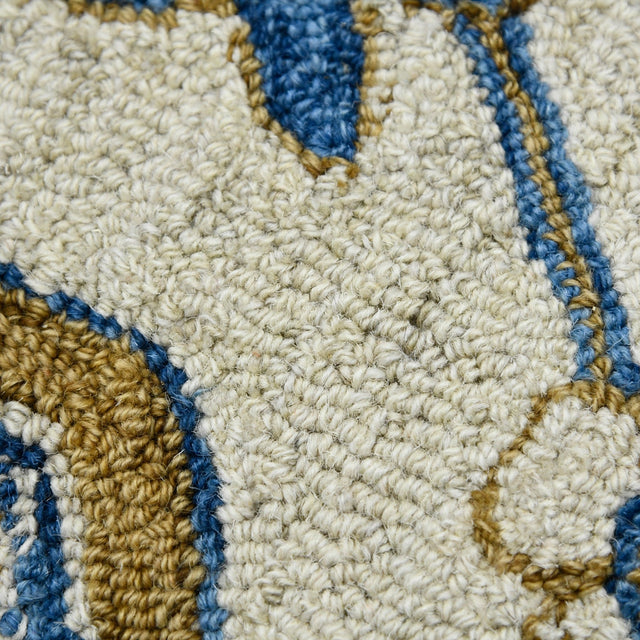 Hand-hooked floral area rug close-up: cream loops with royal blue and gold outline details