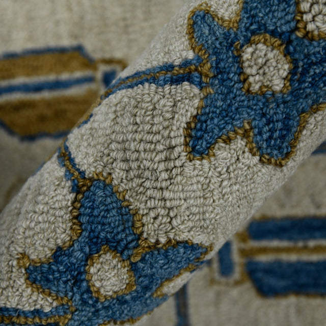 Hand-hooked floral area rug close-up showing raised yarn texture in cream with blue and gold motifs
