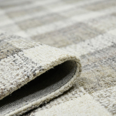 Rug corner detail with layered backing and textured surface in light sand tones.