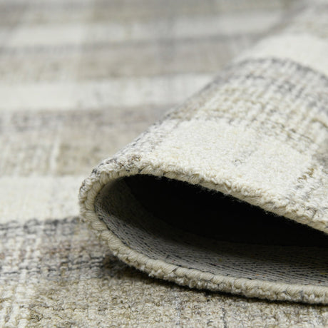 Rug corner rolled edge with backing visible; ivory and gray plaid pattern.