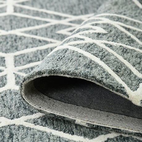 Edge curl close-up: gray rug underside with off-white bordered geometric motif