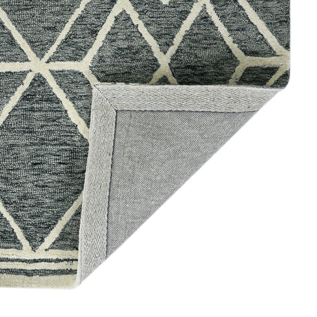 Corner view of gray geometric rug with off-white border and braided-texture edge