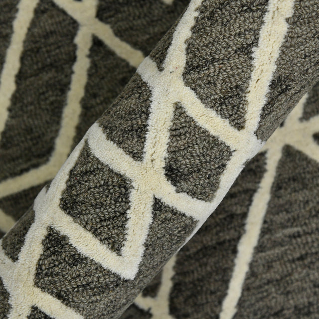 Close-up of hand-hooked rug texture showing off-white geometric lines on khaki.