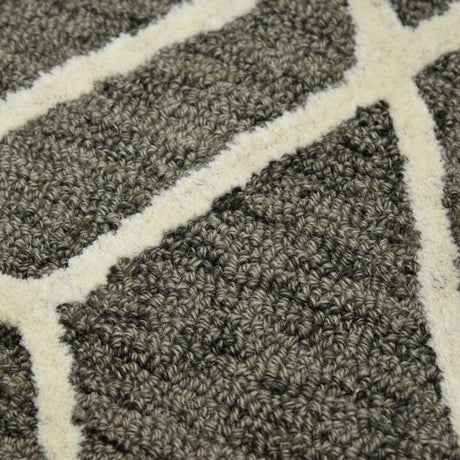 Close-up of hand-hooked area rug texture with dark khaki and off-white pattern motif.