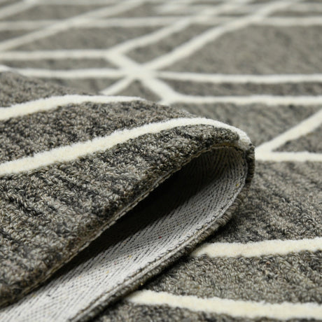 Hand-hooked area rug edge with woven texture and off-white stripe border detail.