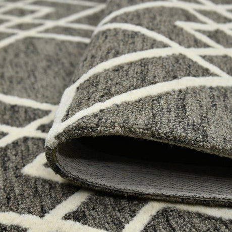 Hand-hooked area rug corner with raised texture and off-white geometric trellis lines.