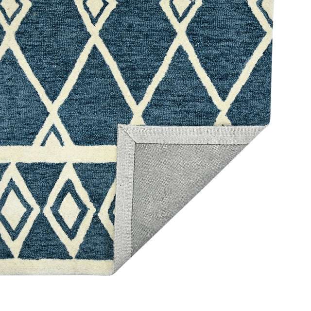 Corner view of navy geometric area rug with cream pattern and folded edge binding