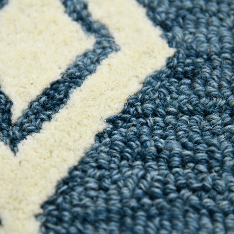 Close-up of hand-hooked rug pile showing navy and cream textured loops