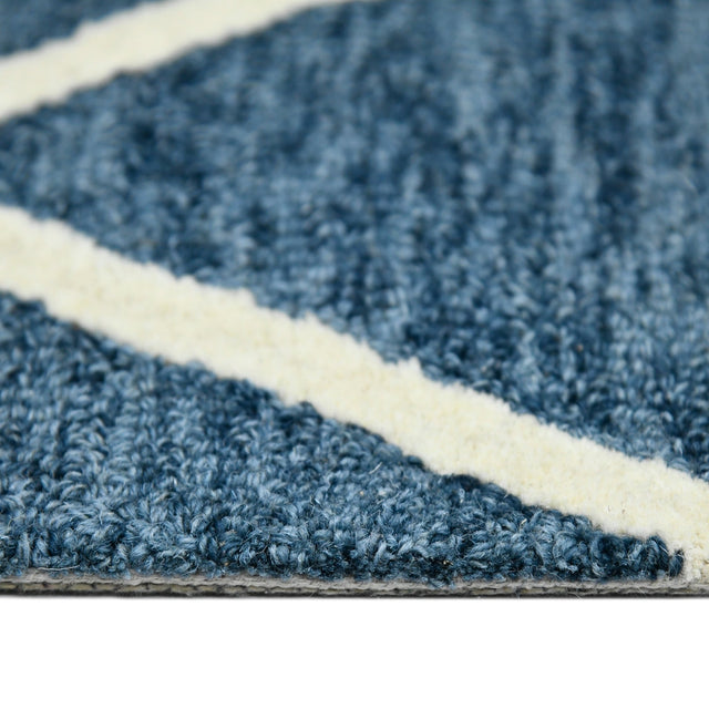 Close-up along rug edge with navy chenille-like pile and cream border stripe