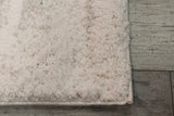 Light grey rectangular shag rug with plush looped texture, detailed corner edge