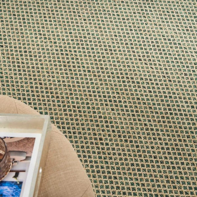 Green rug with repeating diamond lattice pattern and visible edge near furniture