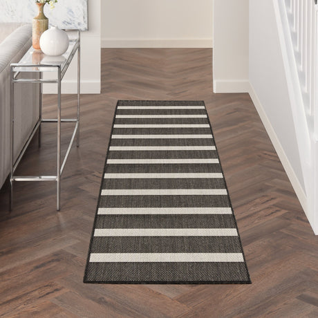 Rectangular black and ivory striped rug with stitched border and low pile