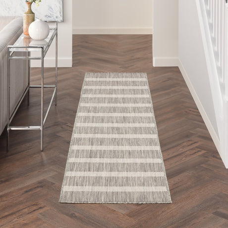 Rectangular grey-and-ivory striped rug laid in hallway on dark wood floor