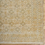 Handmade area rug with ornate geometric pattern in gold, beige, and ivory.