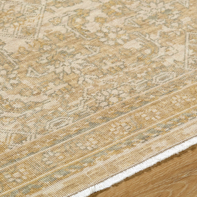 Handmade rug close-up: beige textured weave with gold geometric motifs and bound edge